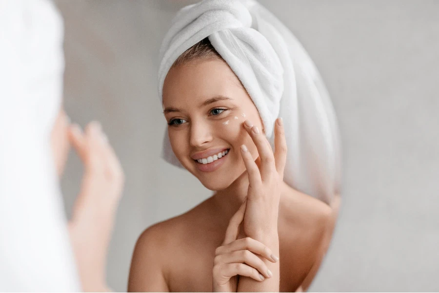 Portrait de jeune femme appliquant une crème nourrissante pour les yeux