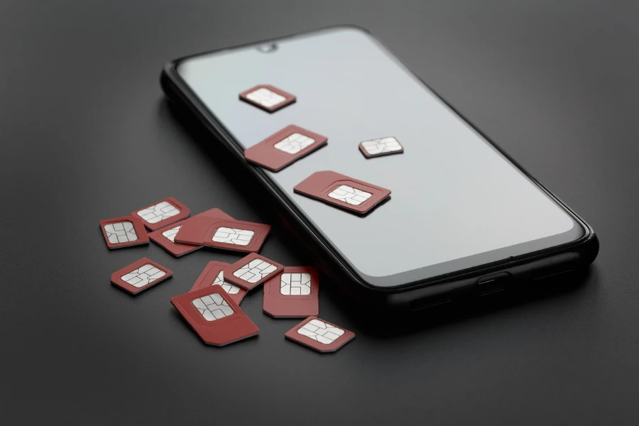 Smartphone dan banyak kartu sim merah dengan latar belakang abu-abu