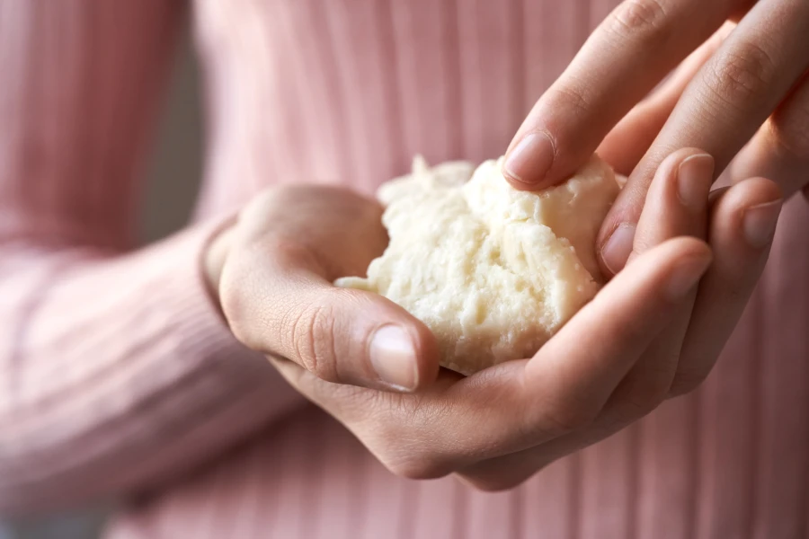 Wanita memegang shea butter mentah atau karite di tangannya