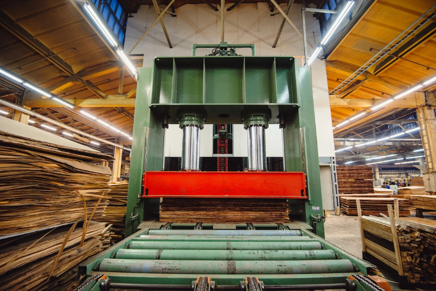 Uma grande prensa hidráulica na oficina, no meio das peças de madeira