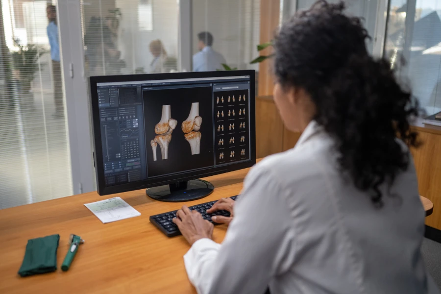 Doctora examinando radiografías médicas en un monitor de computadora
