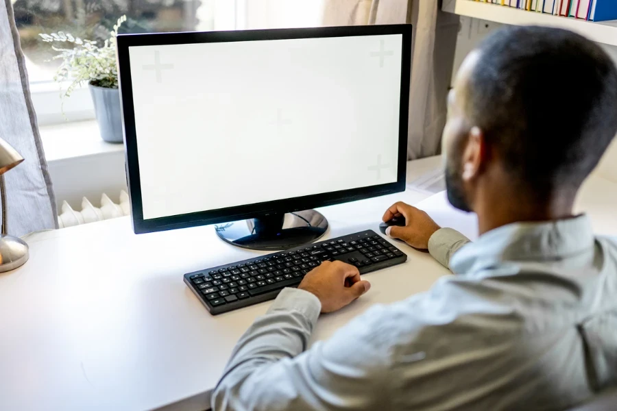 Homme travaillant sur l'écran blanc d'un écran d'ordinateur au bureau à domicile