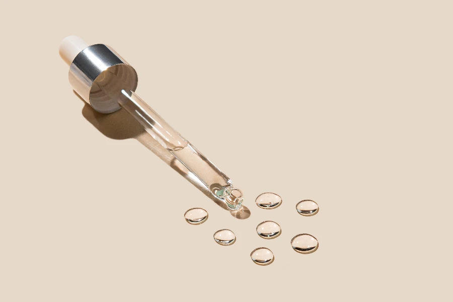 Cosmetic pipette with drops of gel on a beige background
