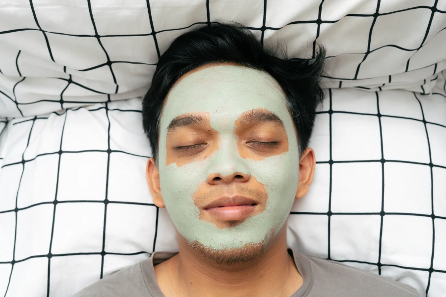 Porträt eines asiatischen indonesischen Mannes, der eine Matcha-Maske aus grünem Tee auf sein Gesicht legt