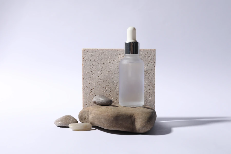 Composição com frasco de soro cosmético em fundo branco