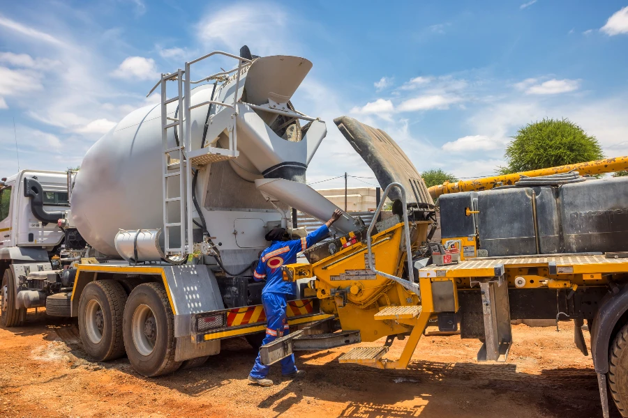 Trabajador africano en un sitio de construcción cargando la bomba de hormigón con pluma