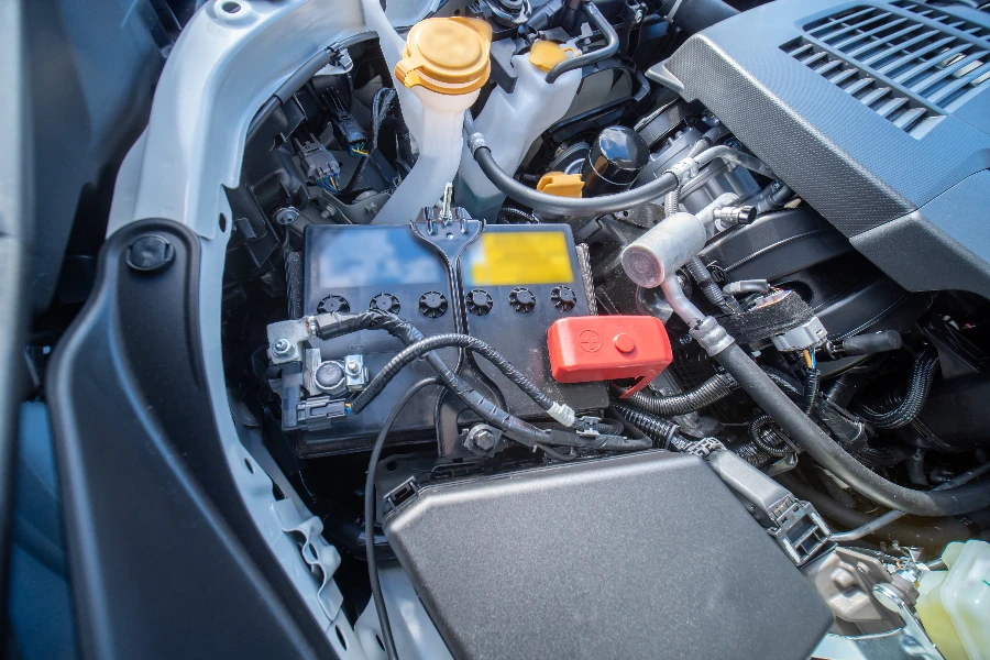 Vista de la batería de 12 V del automóvil debajo del capó en el compartimento del motor