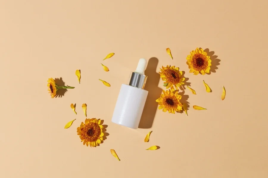 A glass bottle with dropper displayed with small petals and several Calendula flowers
