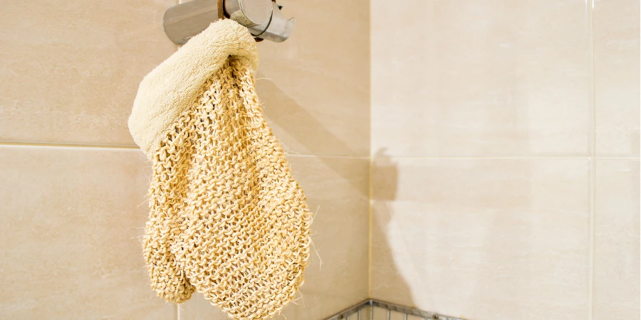 guante exfoliante colgado en la ducha en el baño con copyspace