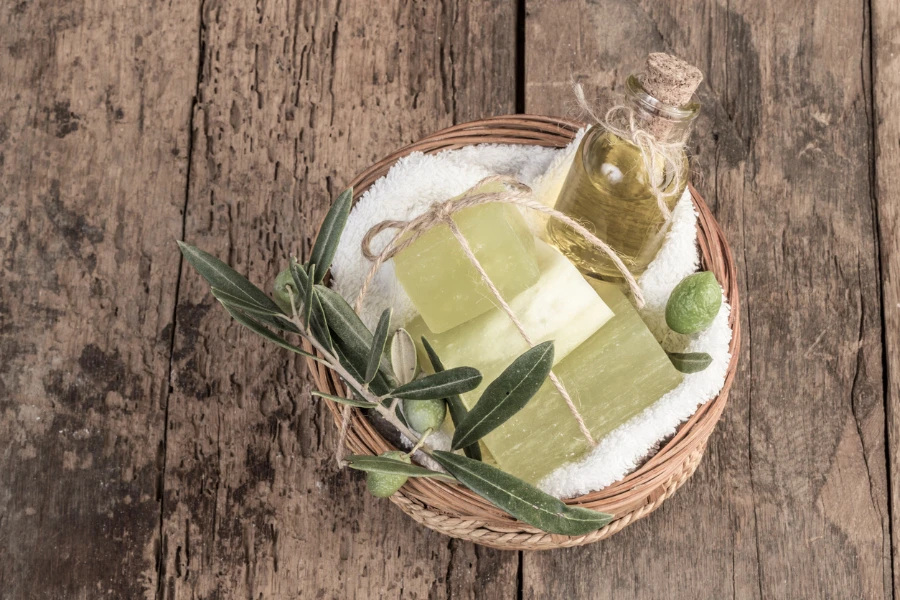 natural olive oil soap bars and olive oil bottle in a basket on wooden table
