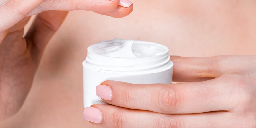 partial close up view of female hands holding eye cream