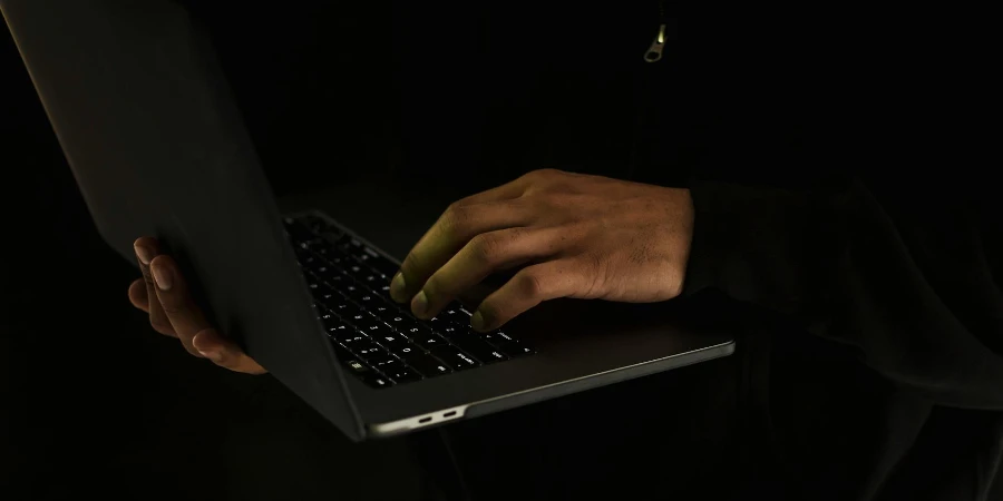 Ein nicht wiederzuerkennender Mann benutzt in der Dunkelheit einen Laptop