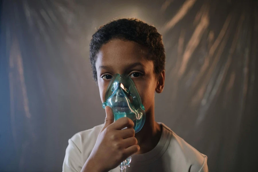 Un Garçon En Chemise Blanche Tenant Un Masque à Oxygène Vert