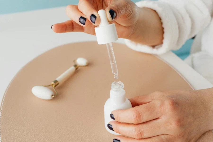 Gros plan d'une femme tenant une pipette avec un produit cosmétique