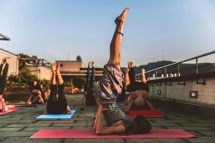 Gruppo di donne sdraiate sul tappetino yoga sotto il cielo blu