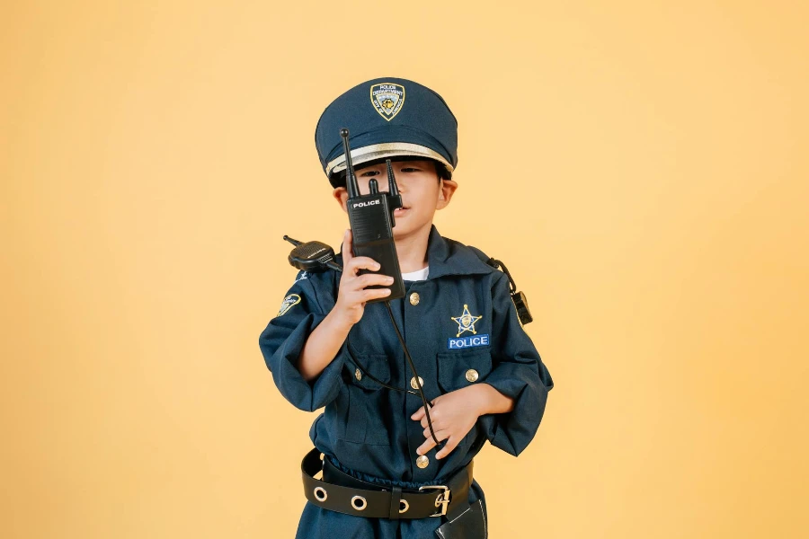 Menino asiático em uniforme policial contra fundo amarelo
