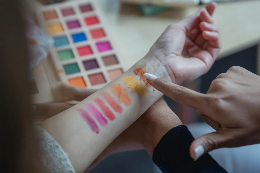Kırpmanın üstünden tanınmayan genç kadın makyaj sanatçısı kolu işaret ediyor