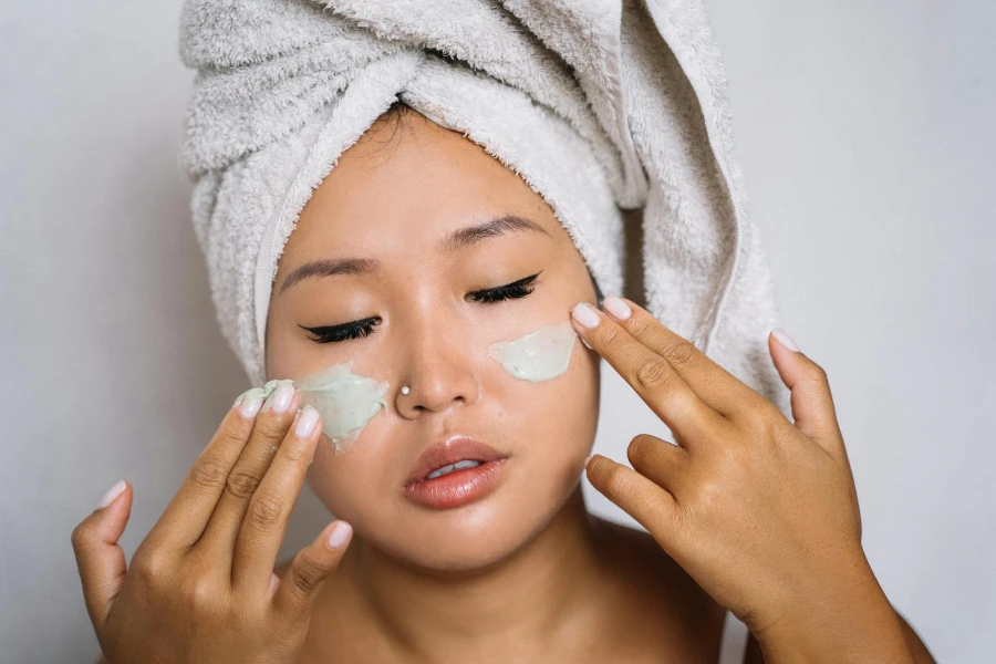 Una mujer aplicándose un producto cosmético en la cara.