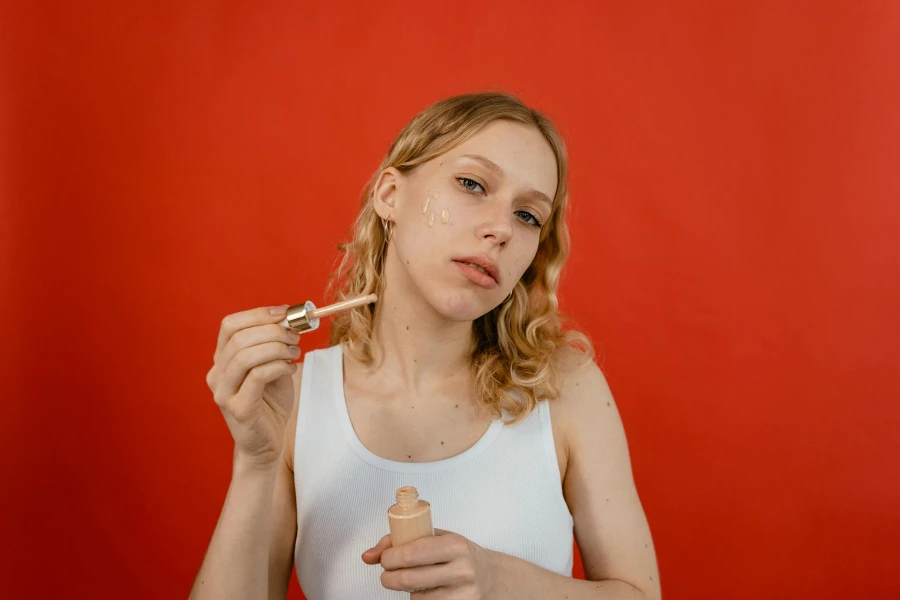 Woman in White Tank Top Holding Glass Container with Brown Cream