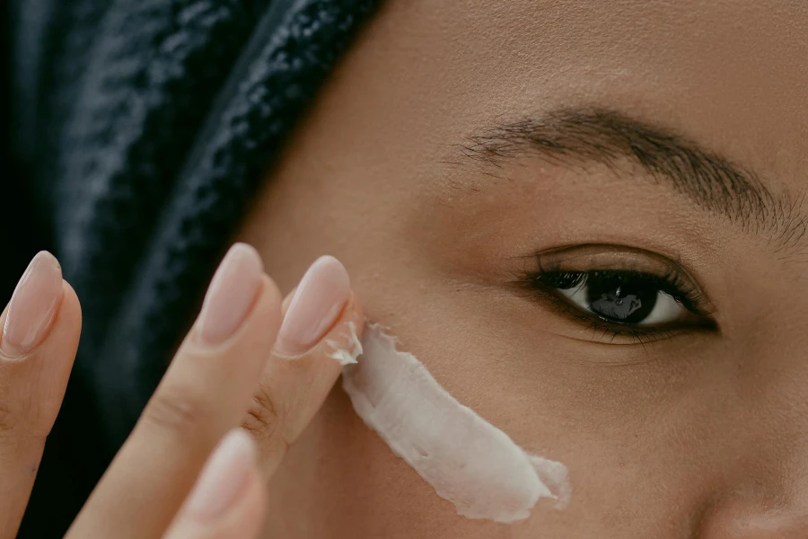 Mujer aplicando crema para los ojos en la cara
