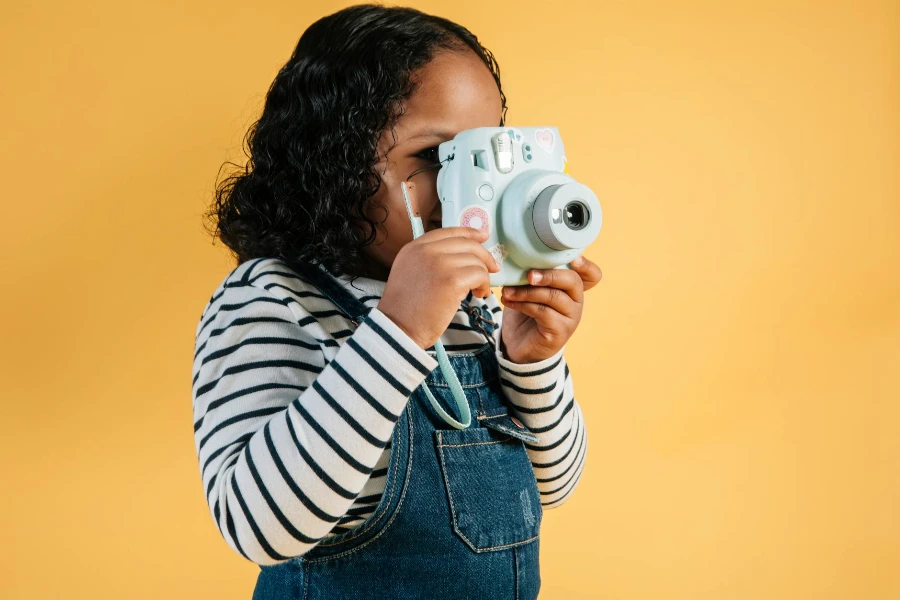 Petite fille afro-américaine concentrée en tenue décontractée prenant des photos