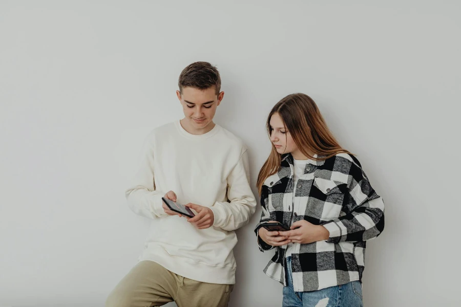 Ritratto in studio di due adolescenti con i telefoni