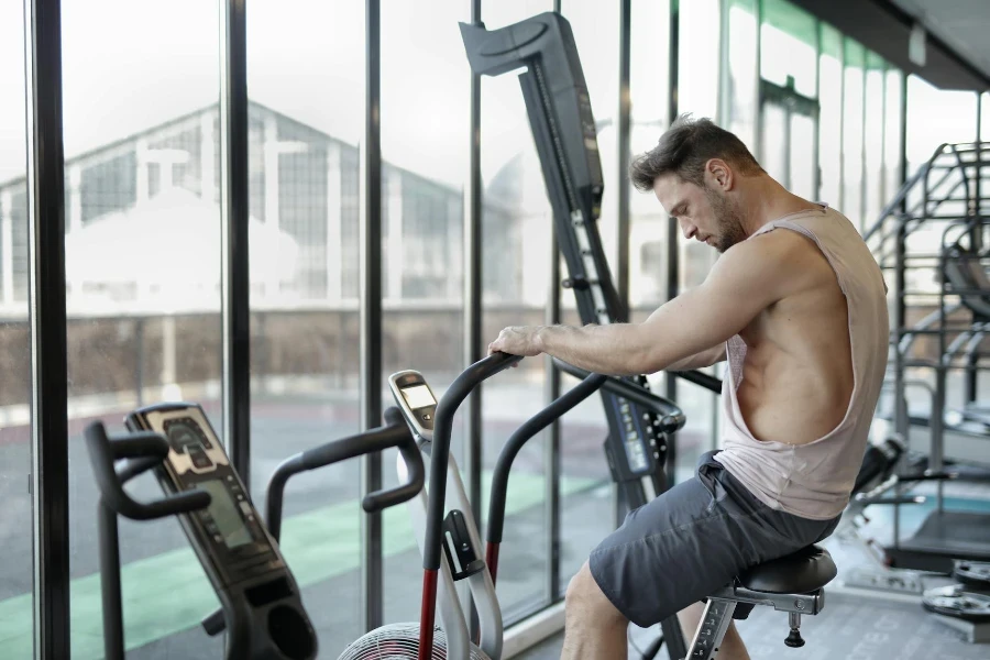 Deportista fuerte usando bicicleta estática en el gimnasio