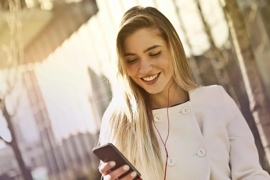 Frau trägt Kochuniform und hält lächelnd ihr Smartphone in der Hand