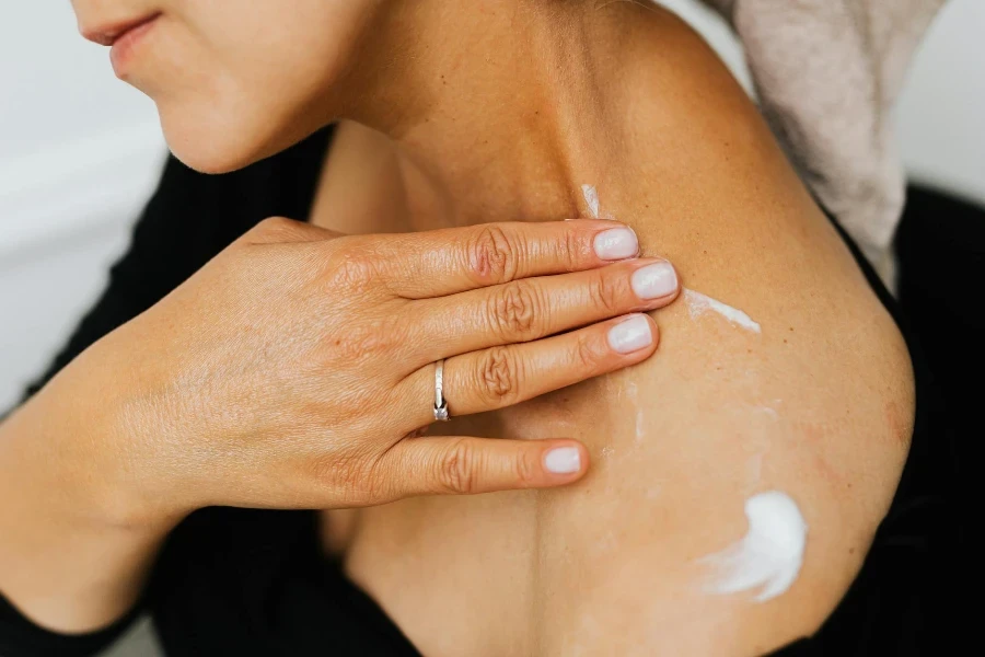 Una donna che applica la crema lozione sulla pelle