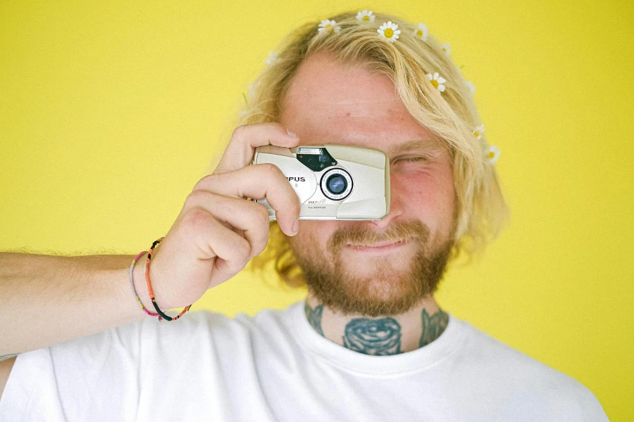 Young male photographer in casual clothes with vintage photo camera