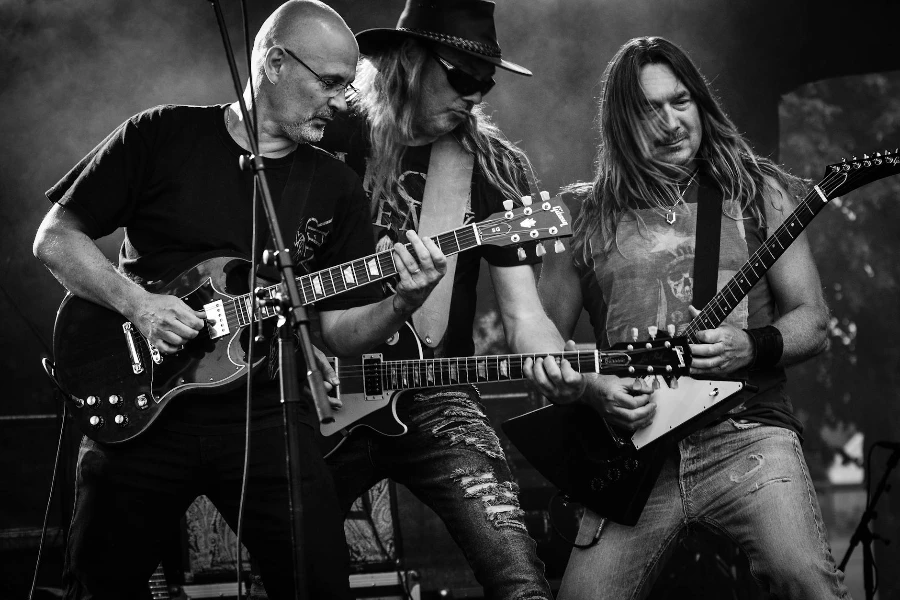 Groupe d'hommes jouant de la guitare lors d'un concert sur une photo en niveaux de gris