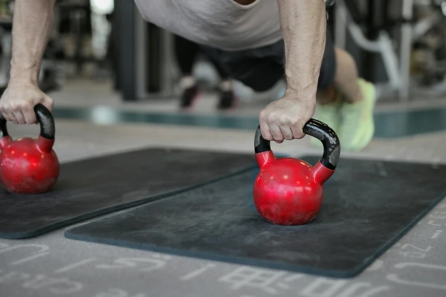 sportsman doing plank exercise on kettlebells