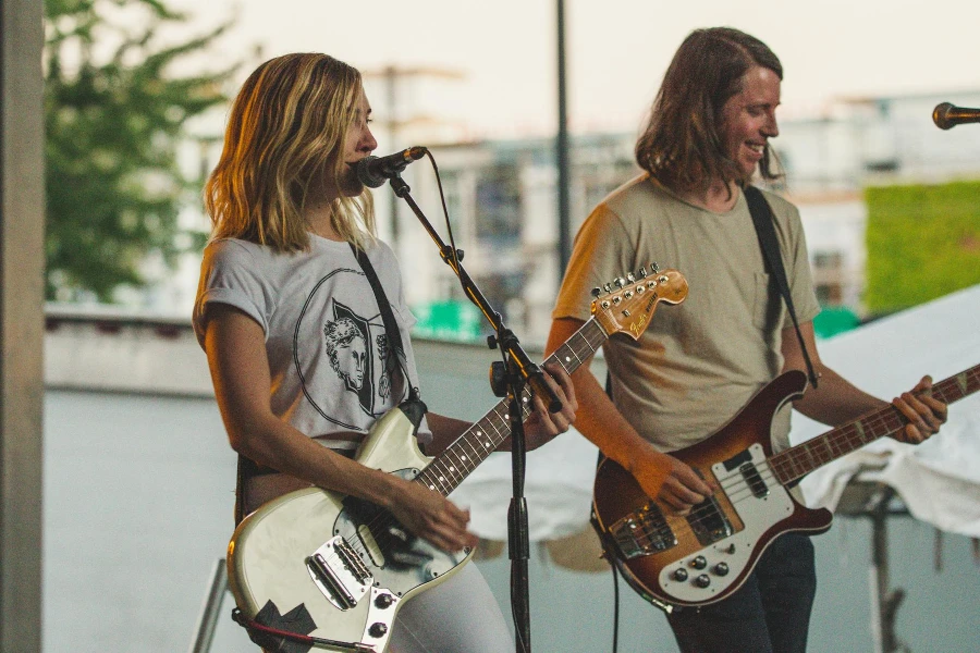 Woman Playing Guitar While Singing Beside Man