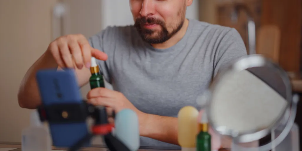 Man applying serum in front of a camera