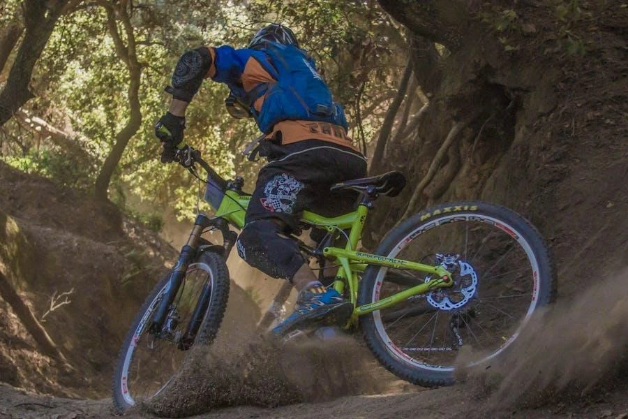 Persona en bicicleta por un camino de tierra con equipo de protección, incluidos guantes