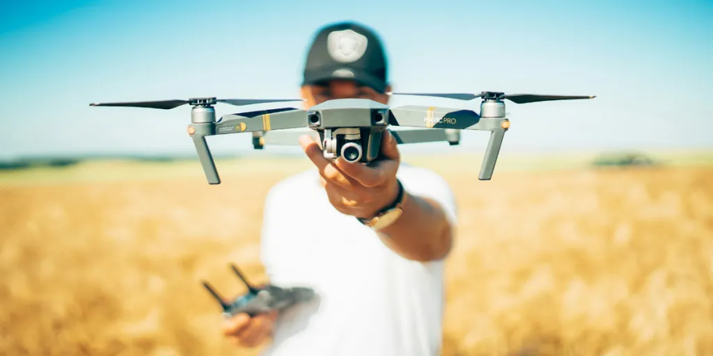 Persona in possesso di un drone in un campo
