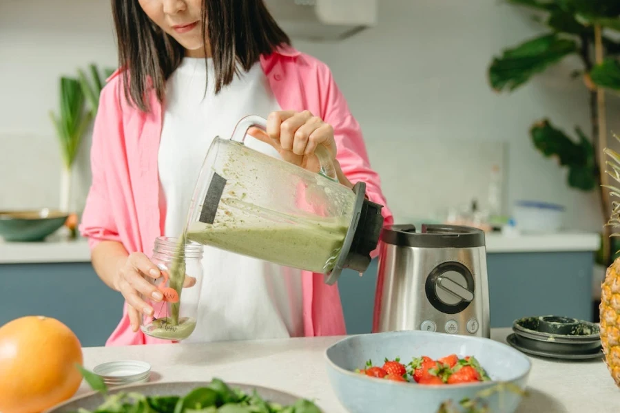 Persona sirviendo un batido verde en una licuadora