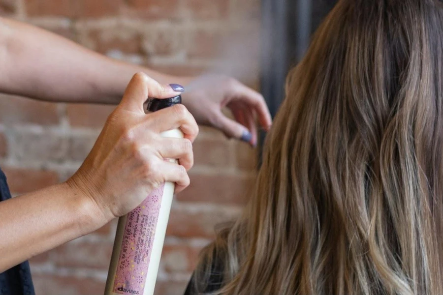 Person using hairspray on a client