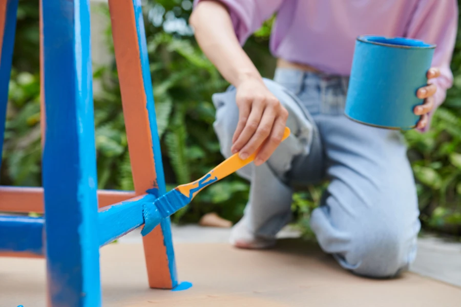 Frau bemalt einen Holzstuhl blau