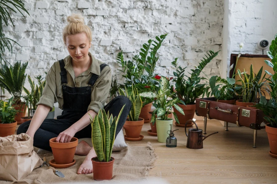 Mujer sentada en el suelo trabajando con plantas.
