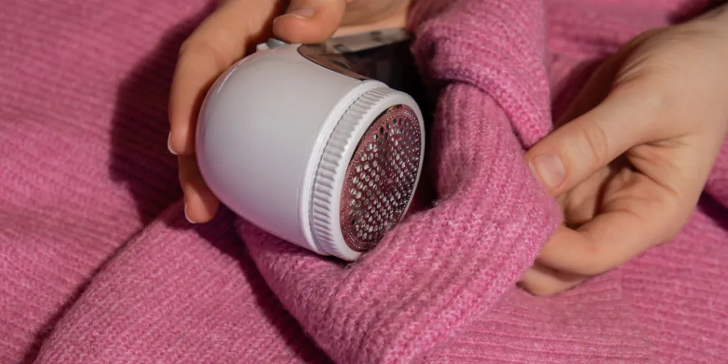 woman using a fabric shaver on her pink sweater