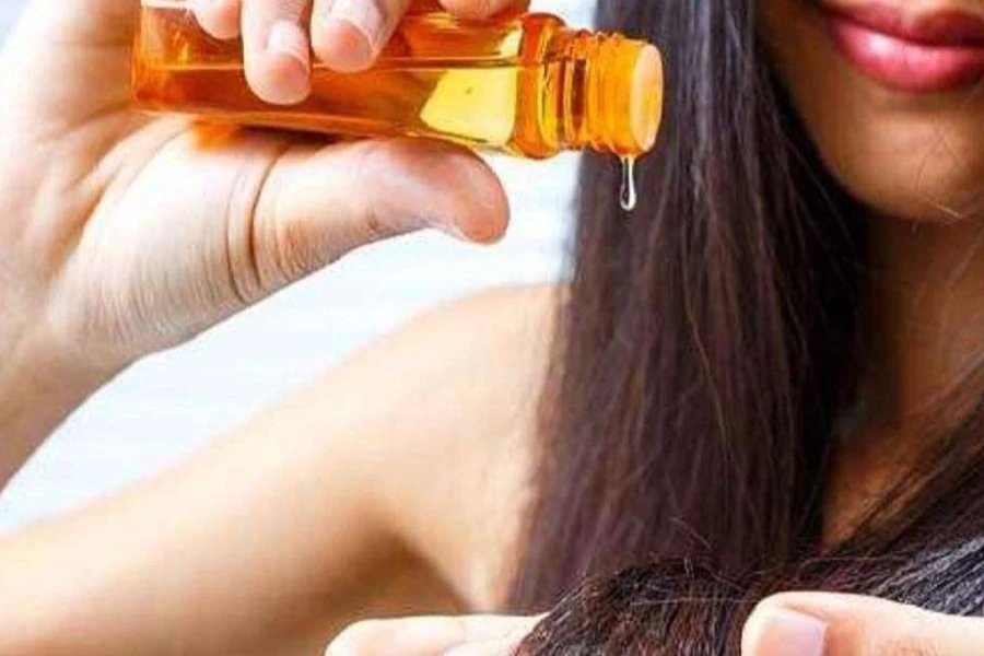 Woman using hair serum on her long hair