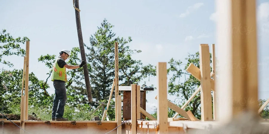 Construction Builder Pumping Concrete Into Wood Frame Forms