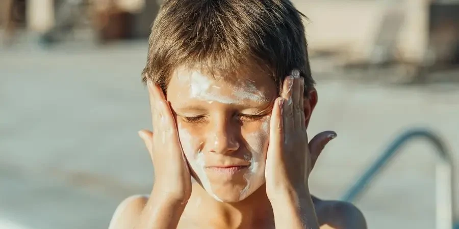 Een jongen met zonnebrandcrème op zijn gezicht door Kindel Media