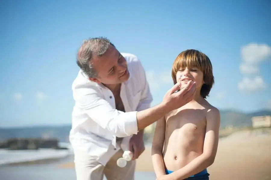 A Man Applying Sunscreen to a Young Boys Face by Kampus Production