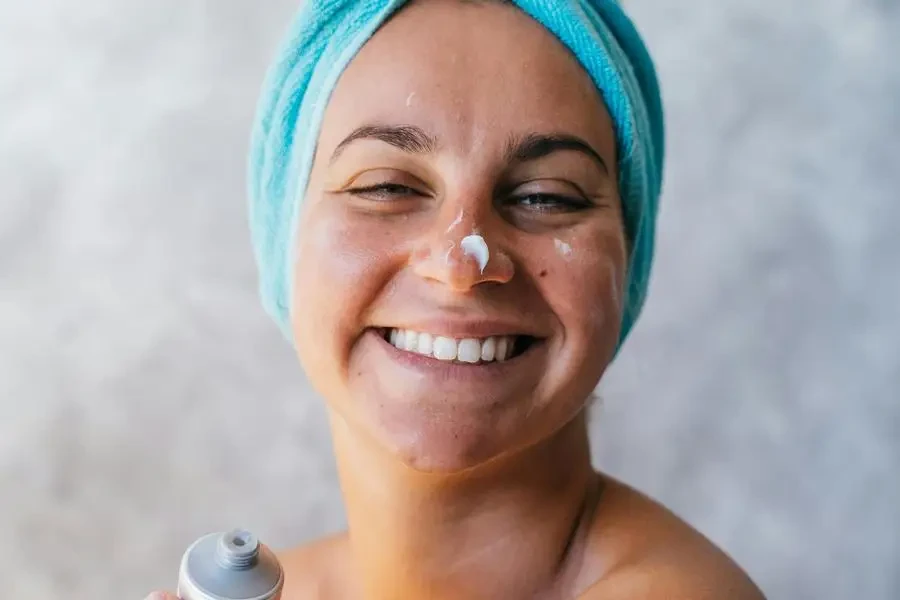 Une femme souriante avec de la crème sur le visage par Anna Tarazevich