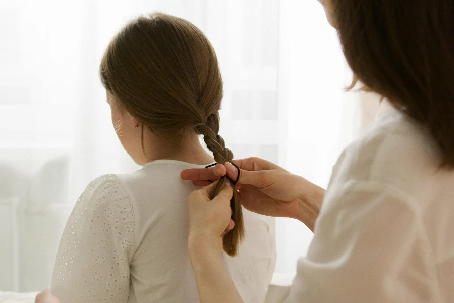 A Woman Braiding Her Daughters Hair