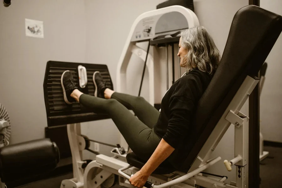 Uma mulher usando uma máquina de leg press em uma academia