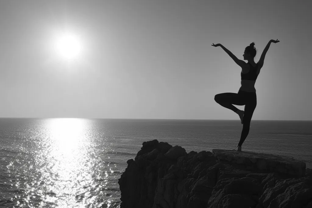 Ein Schwarzweißfoto einer Frau beim Yoga in der Silhouette mit Blick auf das Meer