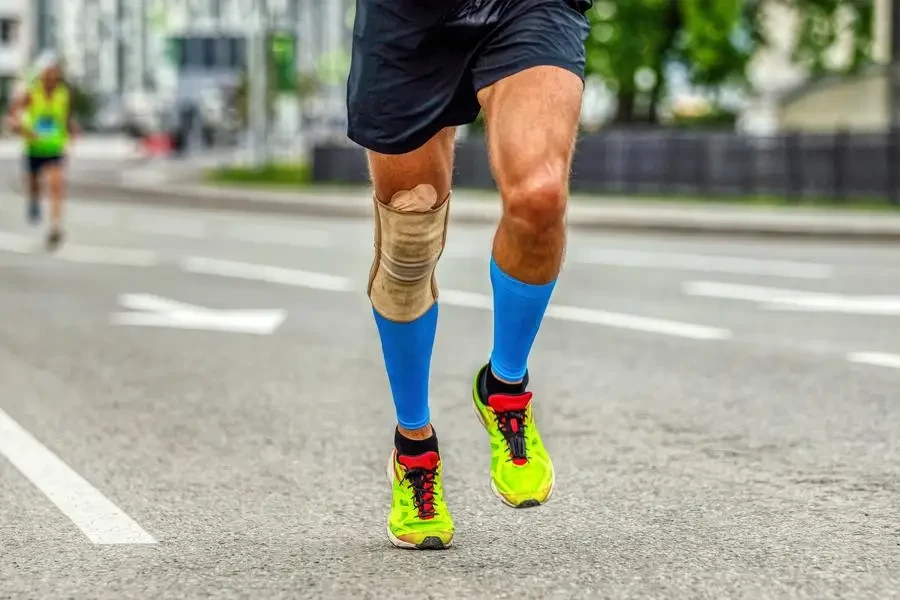 Un homme court avec des manchons de compression aux genoux